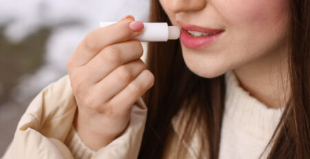 Naine niisutab hügieenilise huulepulgaga huuli, et suunurgad ei oleks katki